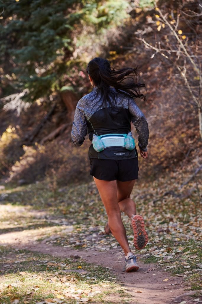 Nadia Ruiz running on a trail wearing the Ultimate Direction waistbelt